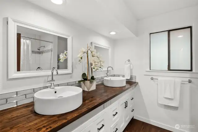 Elegantly remodeled with glass subway tile, raised vessels and white shaker style cabinetry, you will love the ensuite primary bathroom.