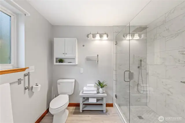 Updated en suite bath features a modern walk-in shower with tile surround and glass enclosure.
