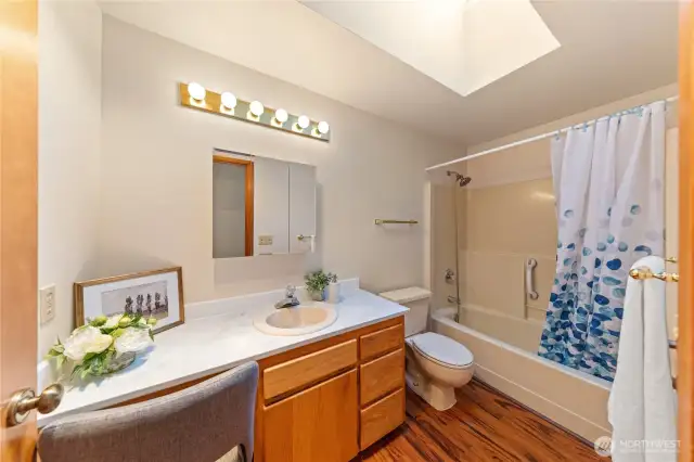 Full guest bath with skylight, tub/shower combo, and extended vanity—conveniently located between the two upper bedrooms.