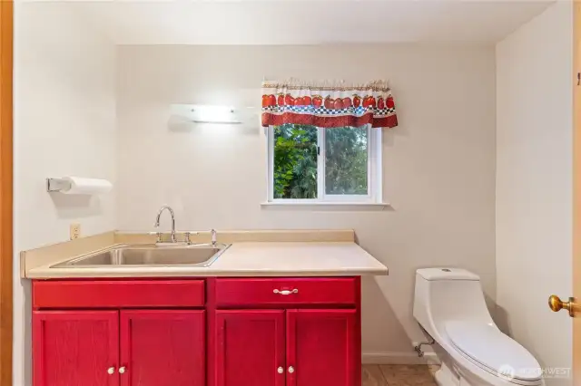 Convenient half bath on the lower level with oversized utility-style sink—ideal for hobbies, art projects, or easy cleanup from the garage or backyard.