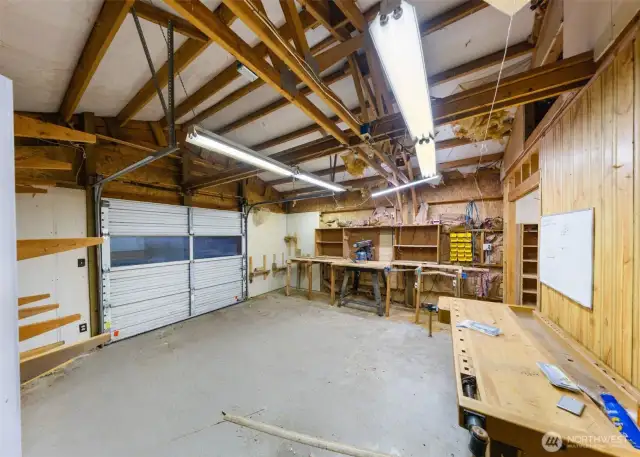 Spacious workshop with garage door access, built-in benches, and power—perfect for woodworking, projects, or extra storage.