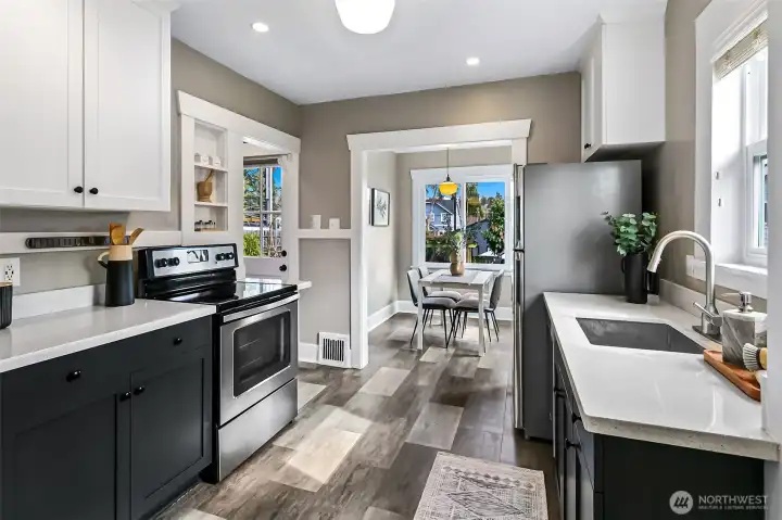 Updated kitchen with quartz counters & stainless appliances opens into the dining room.