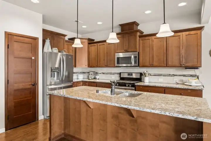 Gourmet kitchen w/ island, slab granite counter tops, SS appliances, and spacious pantry.