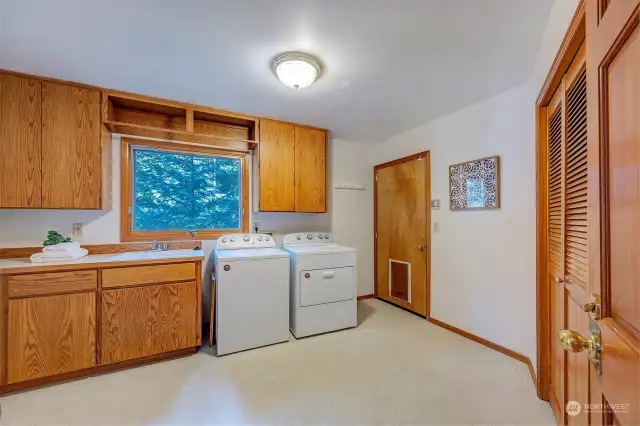 Utility Room/Laundry w/ window overlooking the backyard, built-in cabinetry, & pantry cabinets. Door to garage.