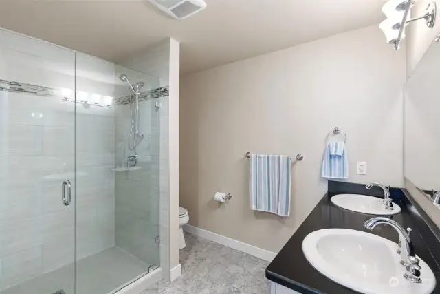 3/4 bathroom with walk-in tile shower & double vanity.