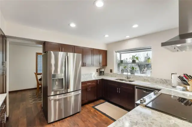 New kitchen view with cherry cabinets undermount ss sink garden window for plants to let even more light in. Door way leads to good sized dining room.  There are no carpets in house for low maintence care. Check out large new ss hood and refridgerator that all stay with home