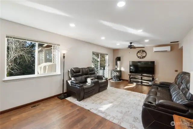 Second view of large great room off kitchen with new soft color paint lots of windows for light and ductless mini split for more heat and AC in summer