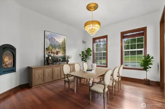 Virtually staged. Grandiose formal dining room with custom chandelier and gas fireplace.