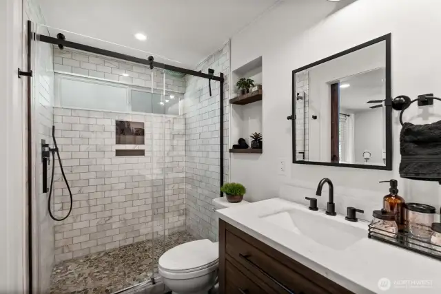 Large walk-in shower with a sleek, matte black-framed glass door.