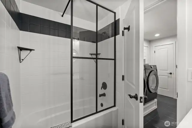 Enjoy a stylish tile-surround tub complemented by a chic matte black-framed glass wall, offering a clean, sophisticated look.