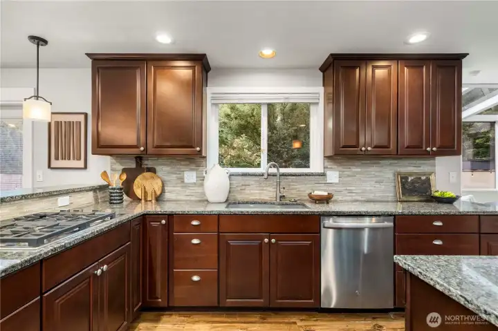 The kitchen features a full-height stone backsplash, stainless steel appliances and custom cabinets with crown moulding