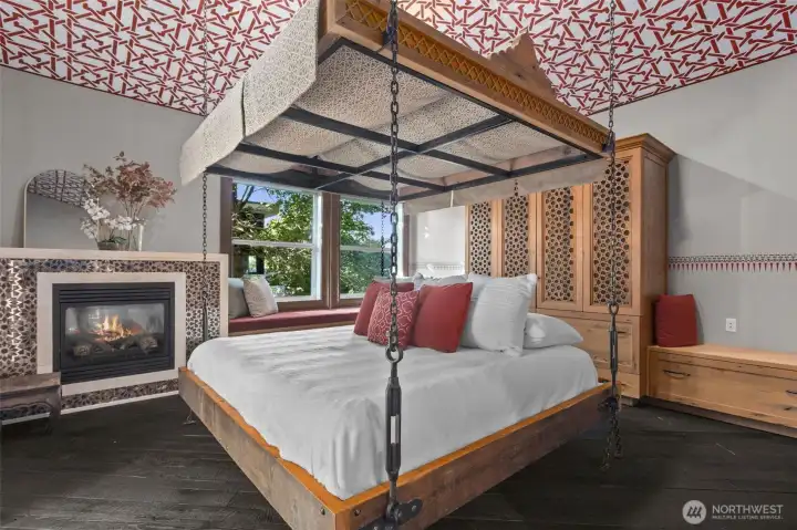 The primary bedroom is a sanctuary of unparalleled design, where every detail has been curated for an extraordinary experience. Hand-stenciled walls and ceilings in timeless Moroccan hues and patterns create a striking, immersive environment, complemented by wood trim, furniture, lanterns, fabric, and tiles imported directly from Morocco. The centerpiece bed is suspended above an “invisible” platform, anchored by ceiling beams, while abundant built-in storage and perimeter benches provide both functionality and refined style.