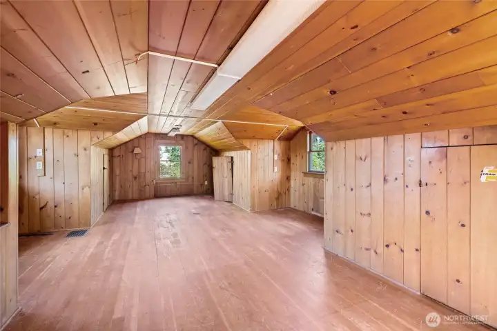 The large upper level bedroom has original wood paneled walls, and fir floors.