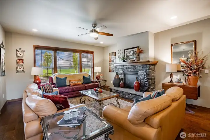 Living room featuring gas fireplace & ceiling fan/light combo that is open to the dining rm & kitchen.