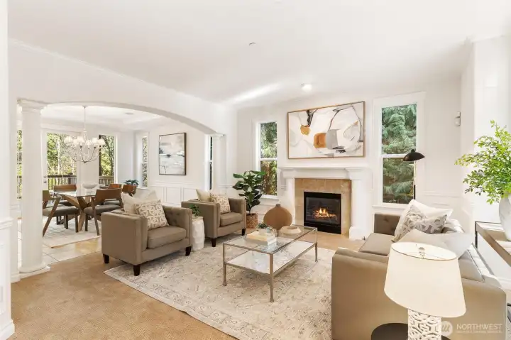 Sophisticated living space featuring a gas fireplace, large windows, and an arched transition to the dining area.