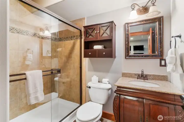 Well-appointed 3/4 bathroom with dark wood vanity and walk-in glass shower.