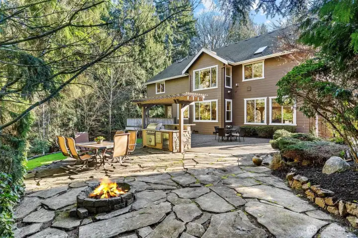 Large stone patio featuring a built-in firepit for year-round outdoor entertaining.