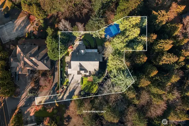 Overhead drone shots showing the secluded, tree-lined lot adjacent to 3 private acres of pristine forest  inc. in HOA.