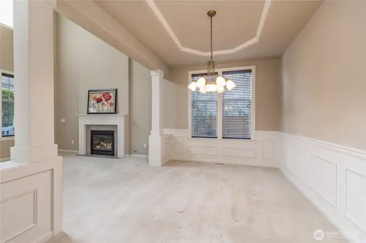 Classy dining room boasts a coffered ceiling, architectural columns and wainscoting