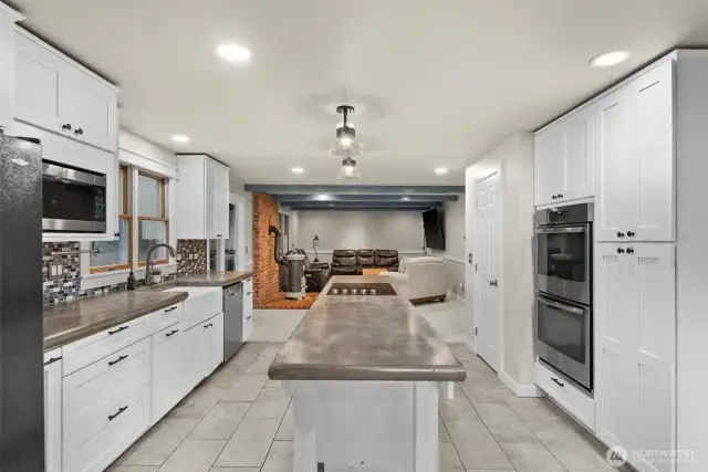 Contemporary kitchen with white cabinetry and sleek finishes. All appliances stay.