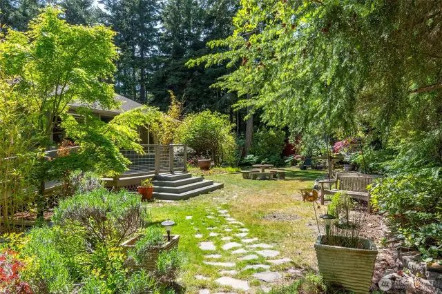 This lovely magical garden has a wide arrange of plants and trees! The covered stone pathway is leading to the front entrance.