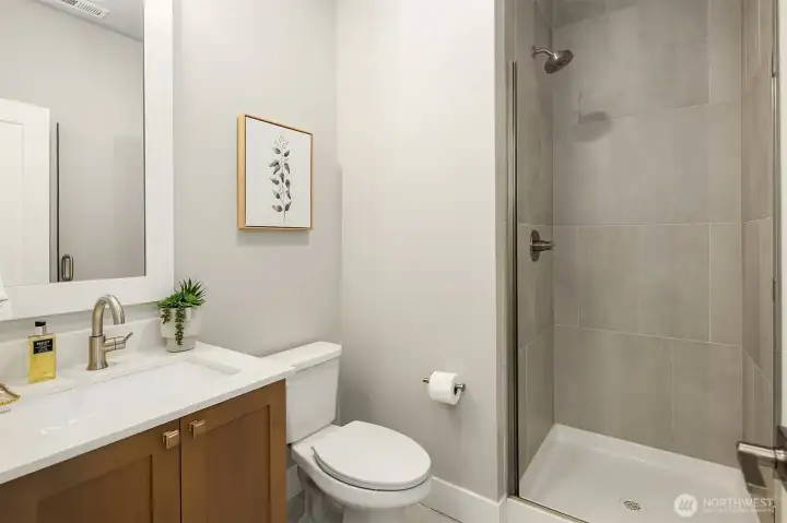 Tile floors and shower with glass door w/white quartz vanity. 1 step from the main level bed or den.