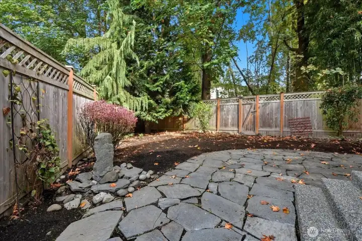 Private back yard with stone patio and newer fencing.