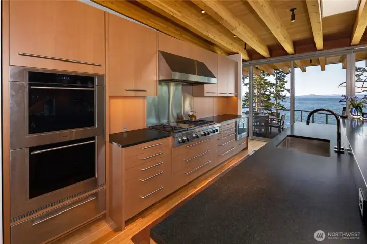 Cooking becomes an experience with panoramic Haro Strait views visible directly from the kitchen, where premium appliances and elegant modern finishes define the space.