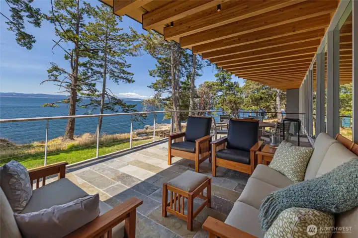 The covered terrace extends the living space outdoors, offering comfortable seating and sweeping views across Haro Strait toward the Olympic Mountains—perfect for year-round outdoor enjoyment.