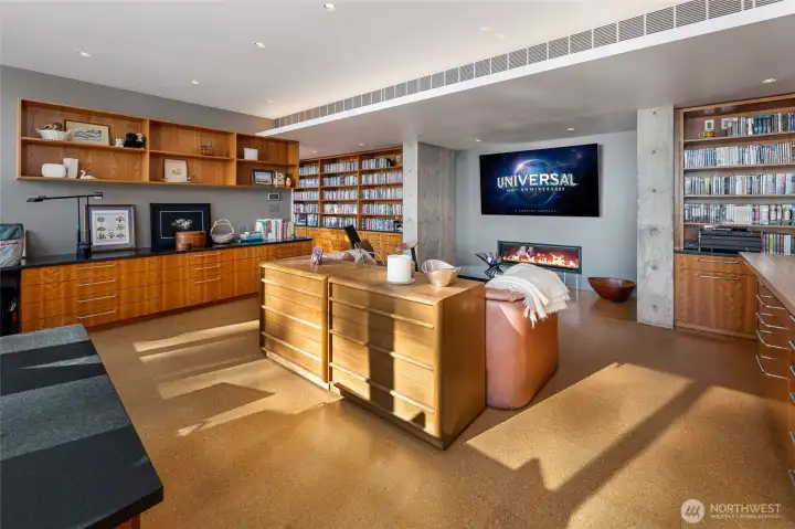 Inviting media lounge with built-in shelving and modern fireplace creates a cozy retreat for movie nights, reading, or relaxing after a day on the water.