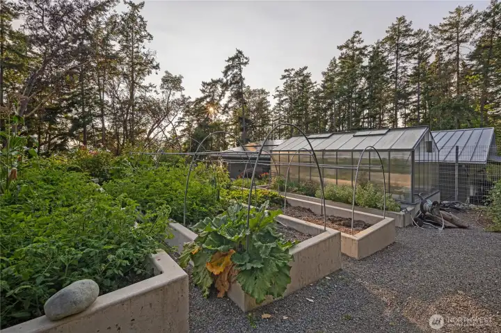 Thoughtfully designed raised garden beds and greenhouse structures provide a beautiful and functional outdoor space for gardening enthusiasts seeking a luxury island property with sustainability in mind.