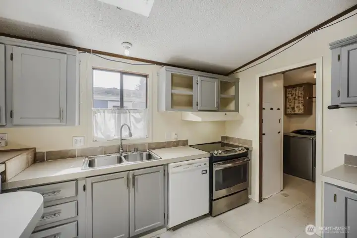 Functional kitchen with ample cabinetry, breakfast bar seating, and skylight bringing in natural light.