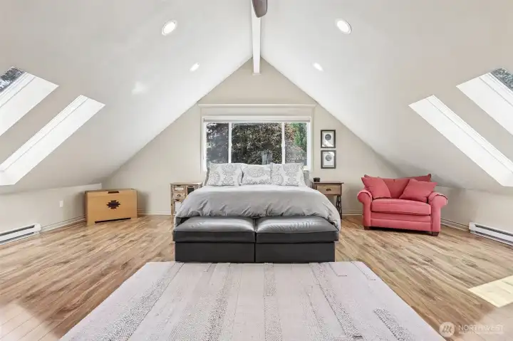 The spacious primary suite features vaulted ceilings, skylights, and expansive windows that fill the room with natural light and peaceful views.