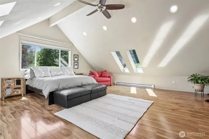 Wake up to peaceful views and natural light in this spacious primary bedroom featuring soaring ceilings and an open, airy design.