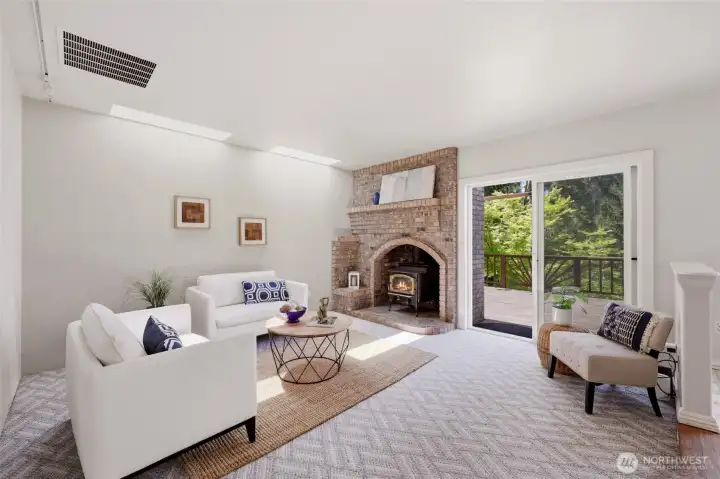Delightfully comfortable family room off the kitchen features skylights, a stately and cozy brick stove and surround, as well as access to the deck--note the styled railing details from here!