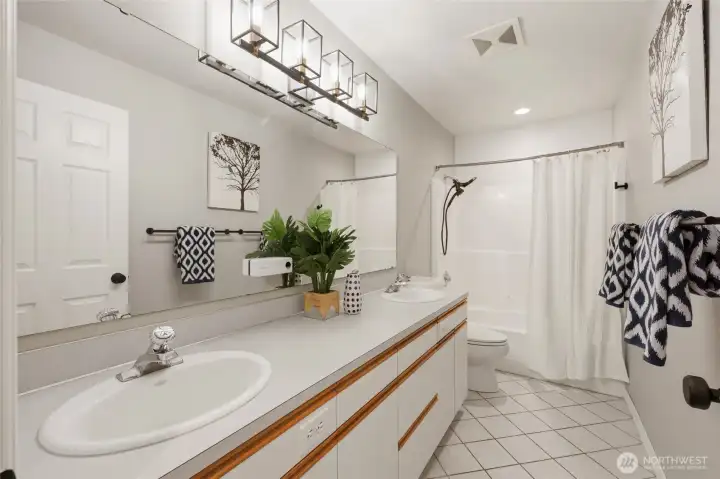Roomy hall bath features diagonal tiled floors, stylish light fixture, cabinet-front outlets, and chute to the laundry room below!