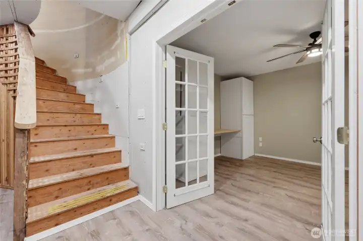 The curved staircase continues its design on the way to the basement level... stair lights guide the path to this partially unfinished space--you'll be amazed at all this level offers! French doors lead to this flex space; closets are found both under the stairs and to the right of this photo, providing ample storage space.