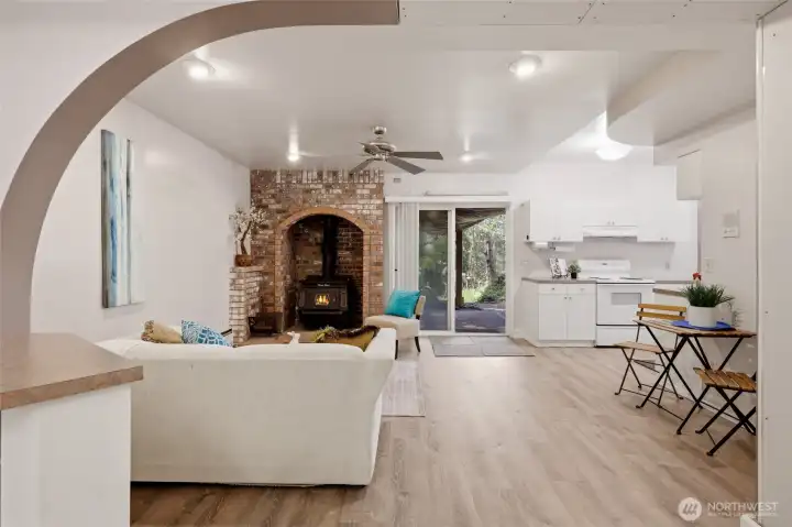 Another woodstove with charming brick surround in this basement living room, along with slider to the lower patio and fabulous property/grounds.