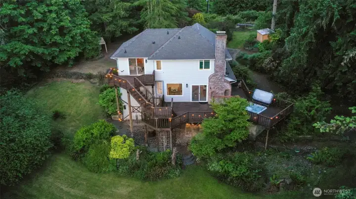 This visual of the house and surrounding greenery gives an idea of how beautiful the property is!  Gardens, greenhouse, and treehouse are found up and to the right: chicken coop, firepit area, and field to the right, large shop and field down and to the right, play structure directly behind the photo... and more!