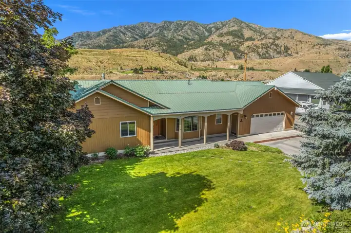 Looking SW from the NE corner! Step outside and take in the incredible beauty of this sprawling, meticulously maintained Pateros property. Featuring a lush front lawn, a welcoming covered porch, and striking mountain views.
