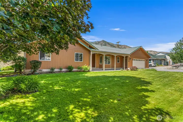 This meticulously maintained single-story home boasts phenomenal curb appeal with a lush, sprawling green lawn and mature shade trees. Featuring an inviting covered front porch, a durable metal roof, and a convenient attached two-car garage, this Methow Valley retreat perfectly blends comfort with its breathtaking mountain surroundings.
