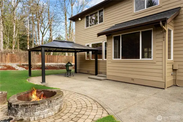 Concrete patio features gazebo cover for entertaining and a built-in fire pit with pavers