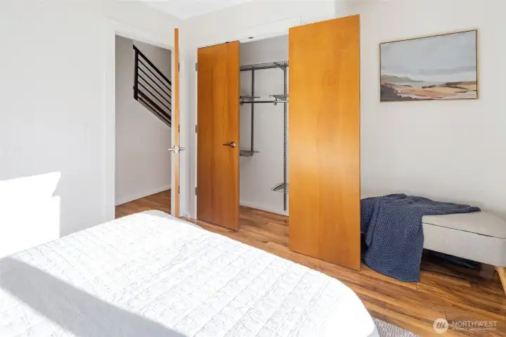 Another angle of the first bedroom, highlighting the roomy closet and a view into the hallway with the stair railing leading to the 4th-floor rooftop deck.