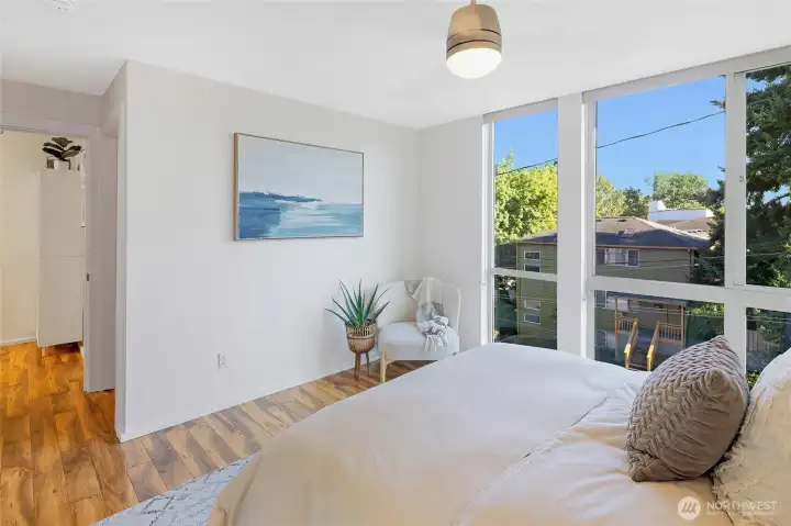 The primary suite feels open and inviting with expansive windows overlooking the treetops. From this view, you can see down into the hallway, with the ¾ bath tucked just around the corner.