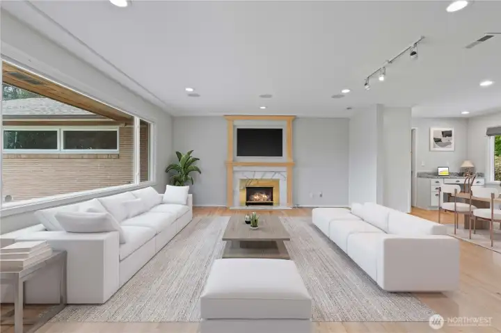 Spacious living room features a cozy gas fireplace, tray ceilings, and large windows that flood the space with natural light. Beautiful hardwood floors complete this inviting space.