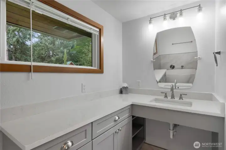 Bright and inviting primary bathroom features a large window that fills the space with natural light, beautifully light fixtures, and a stylish vanity with ADA accessibility for added comfort and convenience