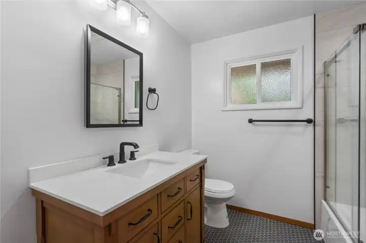 Beautifully remodeled guest bathroom with new tile floors, stylish lighting, and all-new fixtures. Featuring a modern tiled shower and designer touches throughout, this space combines functionality with elegant design