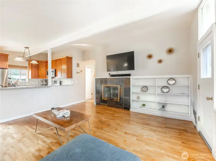 Bright living room with original hardwood floors and wood-burning fireplace.