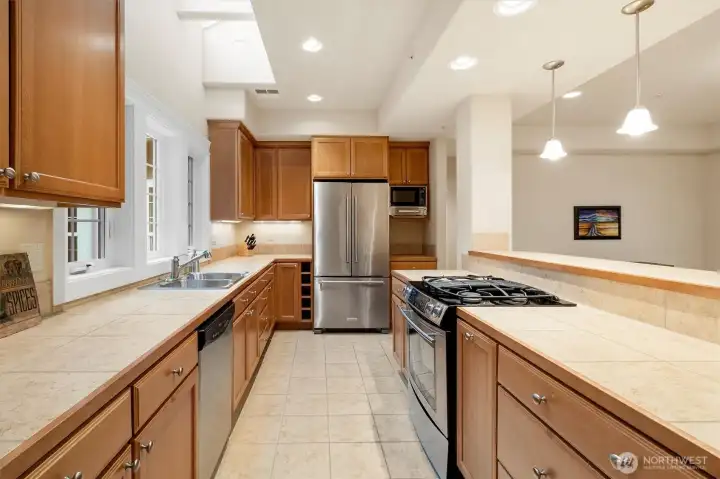 Open kitchen featuring Jenn-Air gas cooktop and oven, KitchenAid refrigerator, Maytag dishwasher, LG stainless steel microwave, and InSinkerator disposal, all complemented by generous counter space and cabinetry.