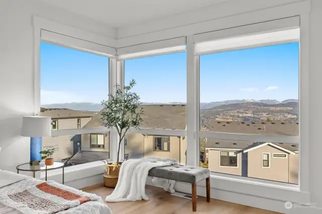 Primary bedroom corner with windows overlooking tranquil views.